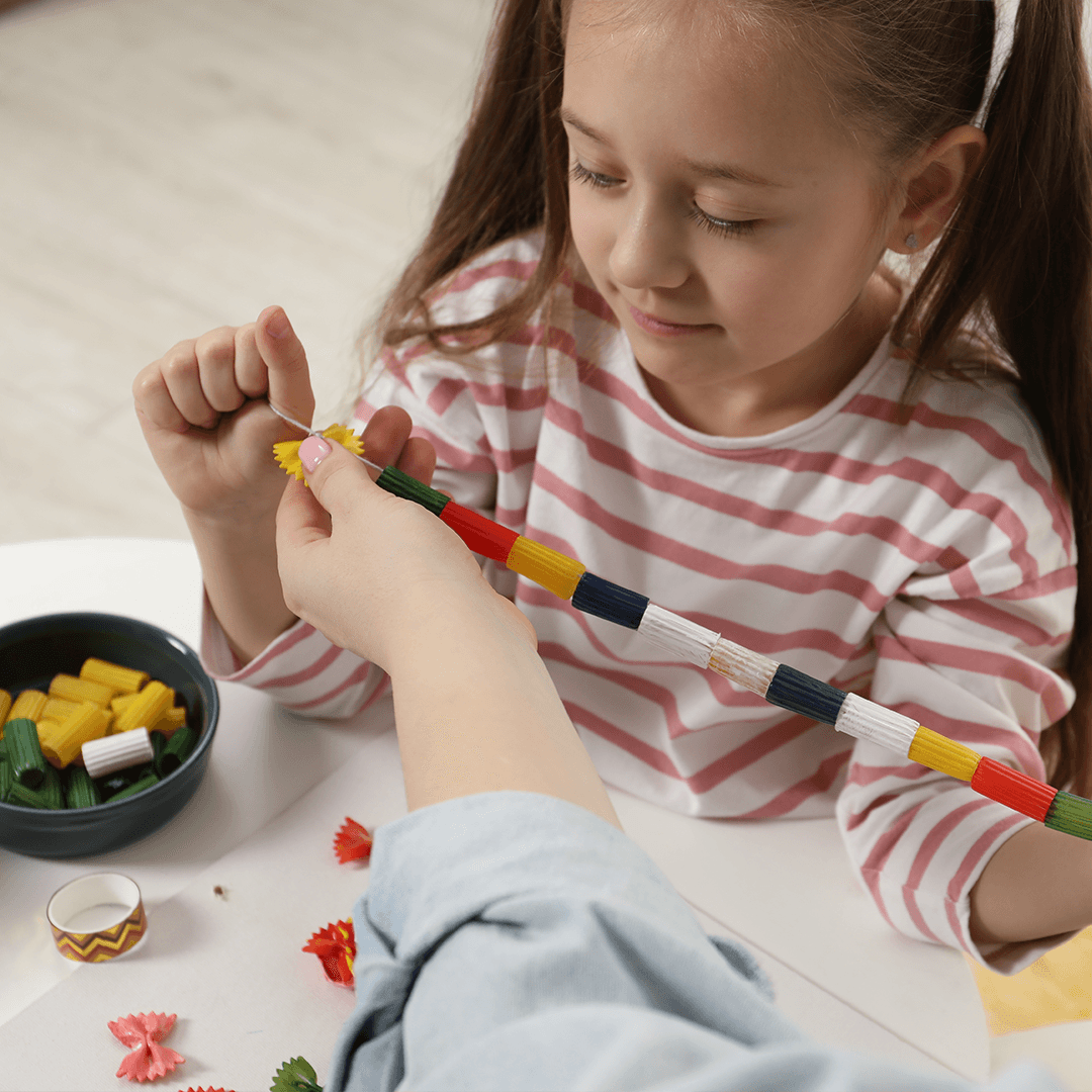 Pige laver pastasmykke med sin mor – hyggelig aktivitet med børn hjemme.