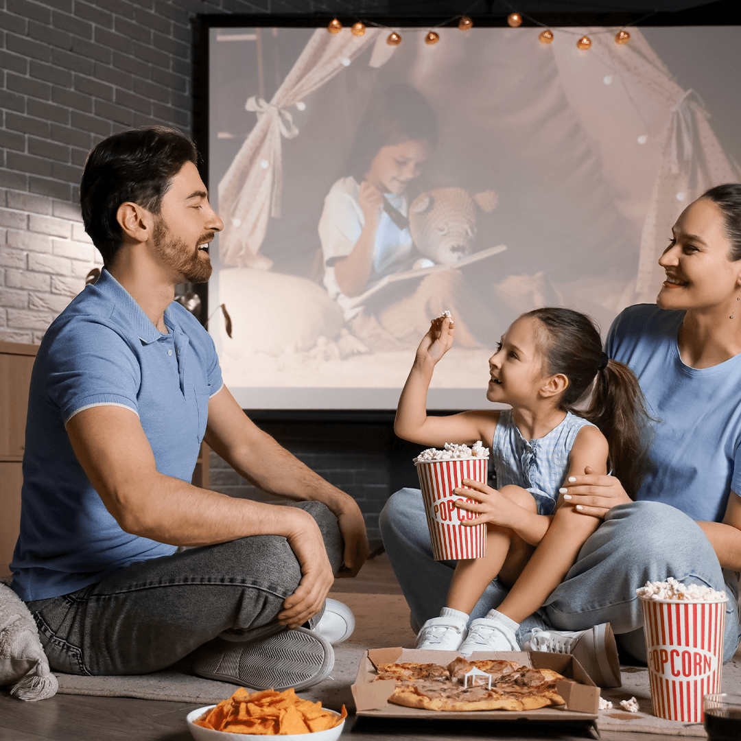 Familien hygger med film og snacks – regnaktiviteter for børn derhjemme.