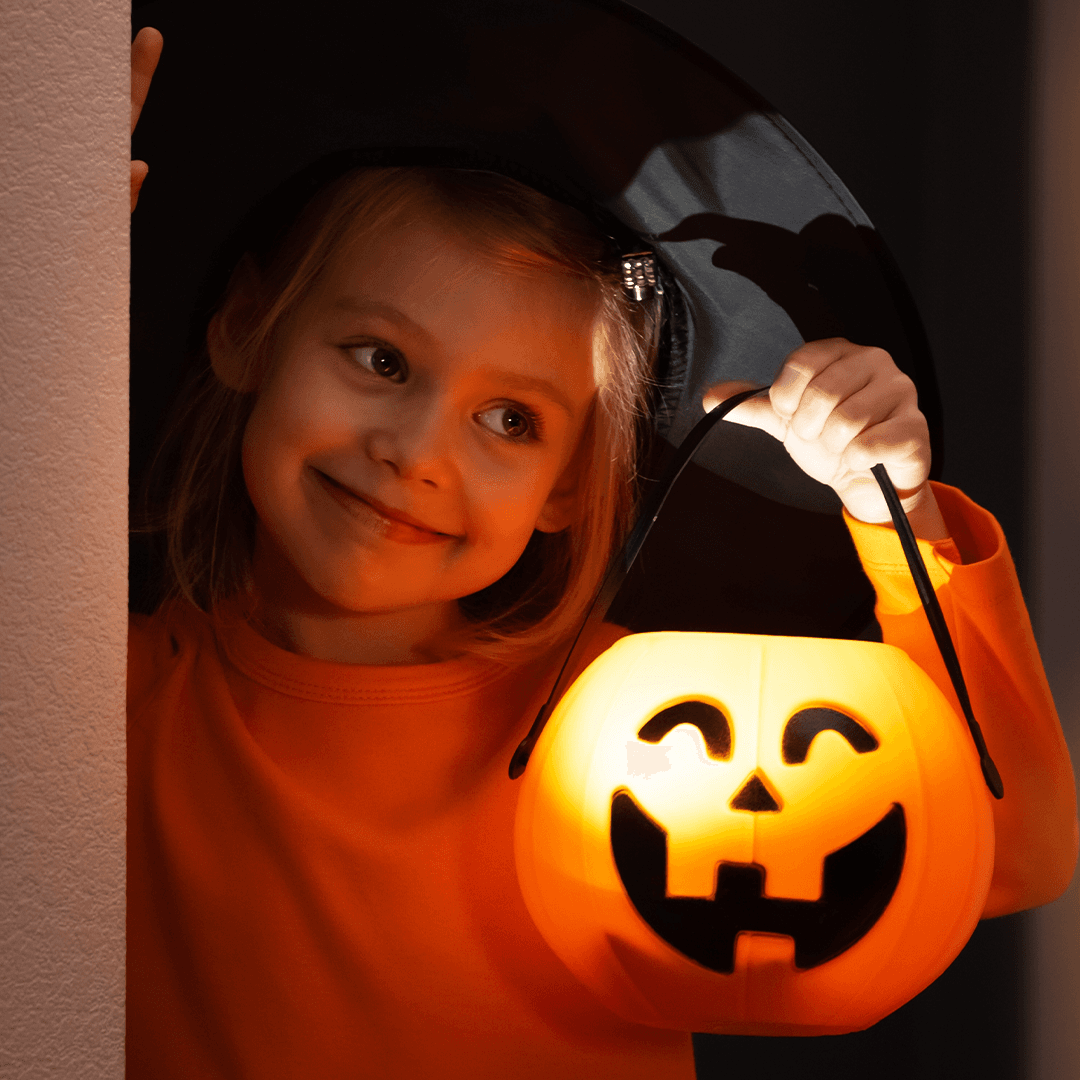 Pige holder en græskarlygte til halloween