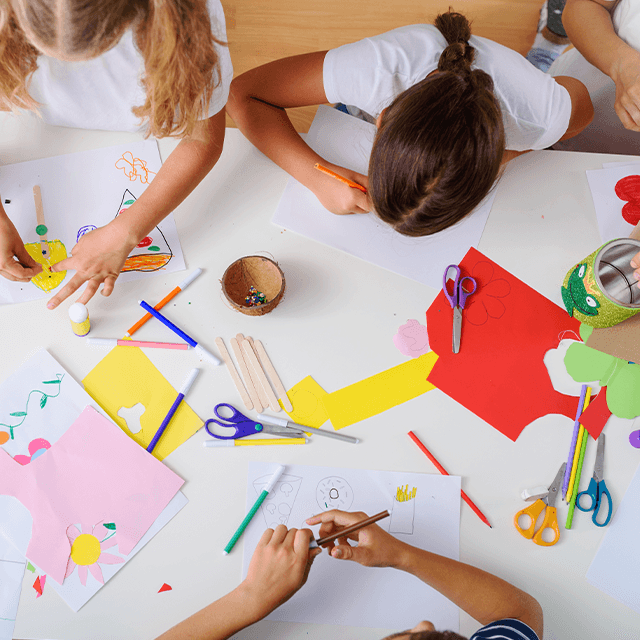 Børn tegner og laver kreative aktiviteter sammen på gulvet
