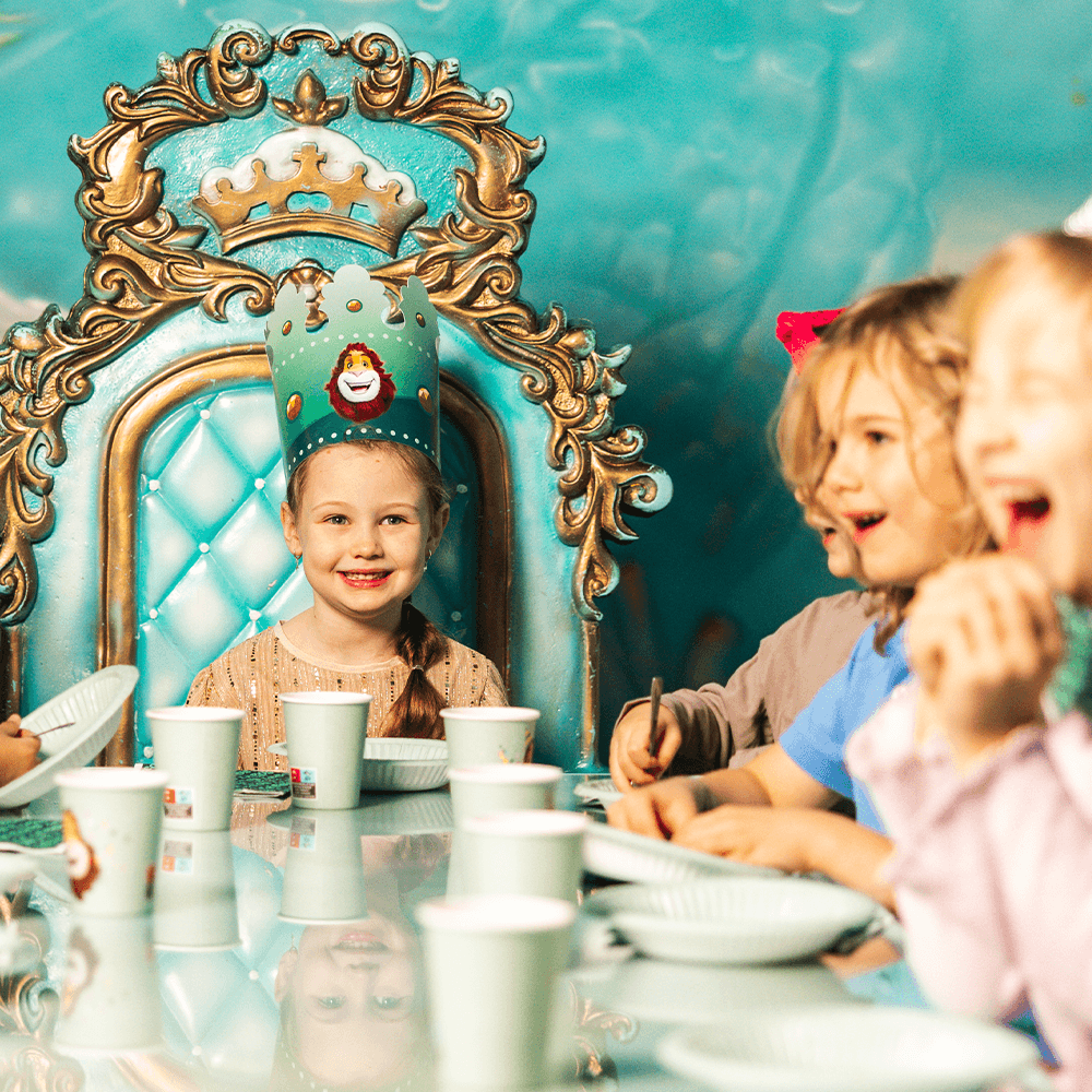 Birthday child sitting happily at the head of the table during a kids birthday party at Leo's